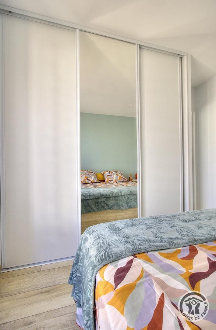 Een slaapkamer met een bed, een kledingkast en een spiegel.