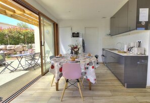 A modern kitchen with a dining area, a microwave, and a view of the garden. - L'Atelier - SAINT VERAND (SAINT VERAND)