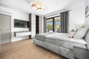 Une chambre moderne avec un lit, une télévision, une armoire intégrée et une fenêtre avec des rideaux.