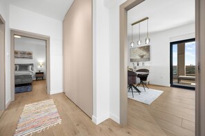 Eine moderne Wohnung mit Bett, Nachttisch und Blick auf die Stadt durch ein großes Fenster.
