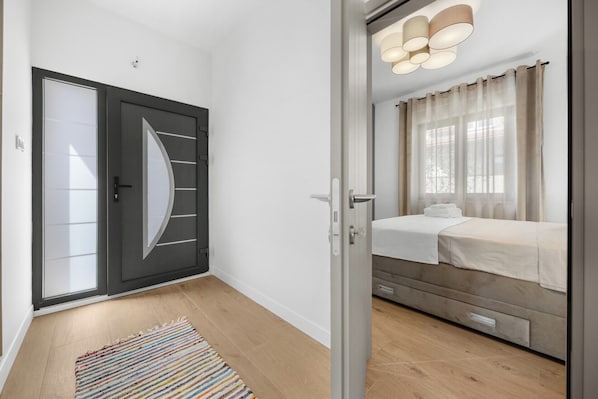 Ein modernes Schlafzimmer mit einem Bett, einem Fenster mit Vorhängen, einer Tür mit kreisförmigem Design und einer Leuchte über dem Bett.