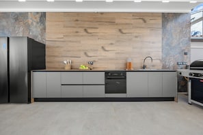 Eine moderne Küche mit eingebautem Geschirrspüler, einem Edelstahlkühlschrank und einem Gasherd.