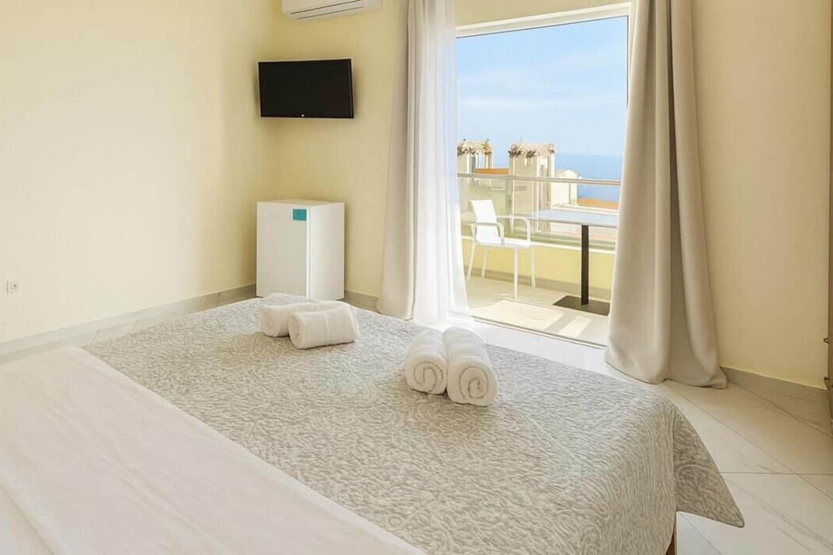 Habitación de hotel con cama, televisión, minibar y balcón con vistas.