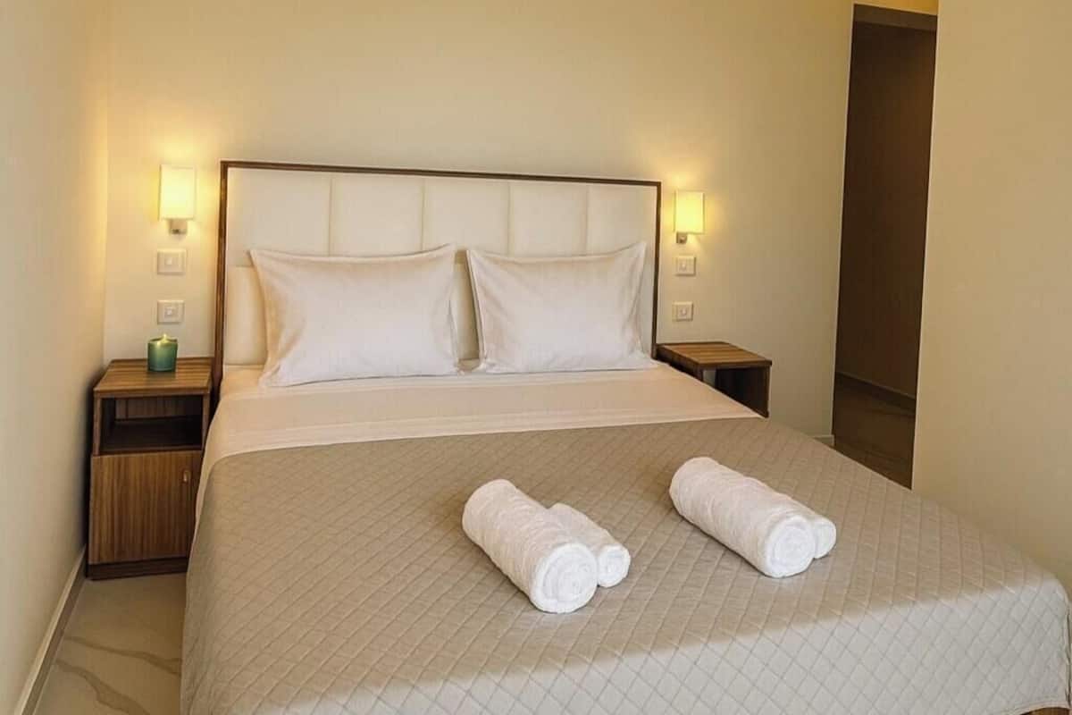 Una habitación de hotel con una cama, dos mesitas de noche y una lámpara de noche.