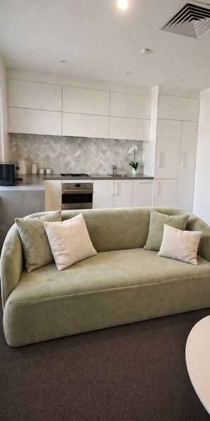 Una sala de estar moderna con un sofá, una cocina al fondo y un comedor.