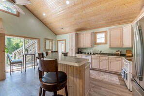 A spacious kitchen with wooden cabinets, a large island, and a built-in refrigerator.