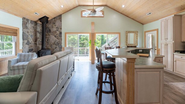 A spacious kitchen with a stone wall, wooden ceiling, and a large island with bar stools.