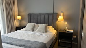 Ein Hotelzimmer mit einem Bett, zwei Nachttischen, einem Kopfteil und zwei Lampen.