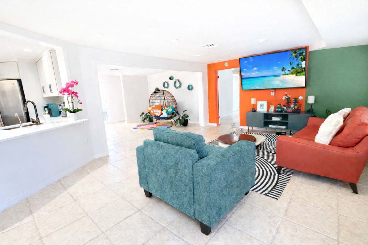 A modern living room with a sofa, a coffee table, and a TV. There is a kitchen area with a fridge and a sink.. Breezy Cove-Spacious, Gulf Access, Near Beaches