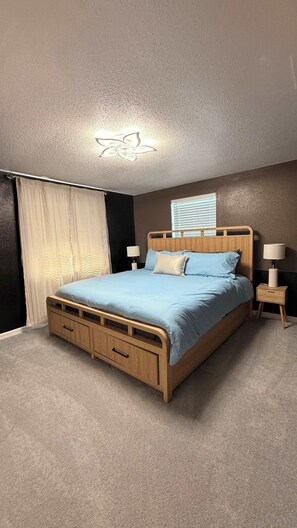 A bedroom with a wooden bed, a ceiling fan, a window with blinds, and a nightstand with a lamp. - Breezy Cove-Spacious, Gulf Access, Near Beaches (Apollo Beach)
