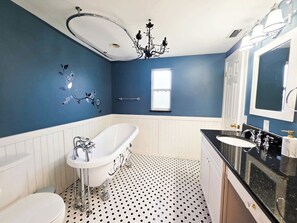 A bathroom with a freestanding bathtub, a toilet, a sink, and a vanity with a mirror. - Breezy Cove-Spacious, Gulf Access, Near Beaches (Apollo Beach)