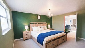 Una camera da letto con un letto, comodini, un lampadario e vista su un'altra stanza.