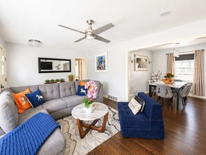 Ein Wohnzimmer mit grauem Sofa, blauem Sessel und rundem Couchtisch.