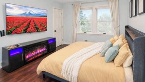 Een slaapkamer met een bed, een televisie, een open haard en een raam.