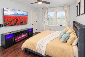 Ein Schlafzimmer mit Bett, Fernseher, Kamin und Fenster.