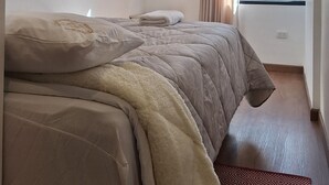 A hotel room with a bed, a window with curtains, and a city view. - A fully furnished, modern, comfortable, and cozy apartment. (Cusco)