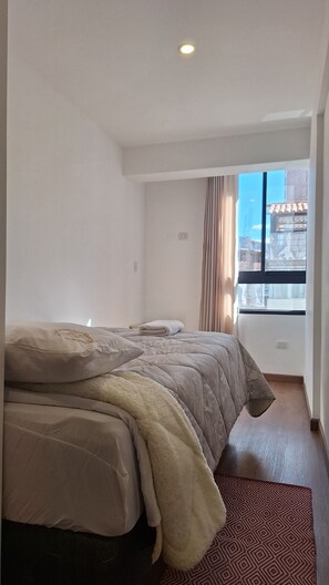 Ein Hotelzimmer mit Bett, einem fenster mit Vorhängen und Blick auf die Stadt.