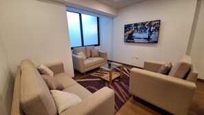 A living room with two sofas, a coffee table, and a TV mounted on the wall. - Fully furnished, modern, comfortable, and cozy apartment. (Cusco)