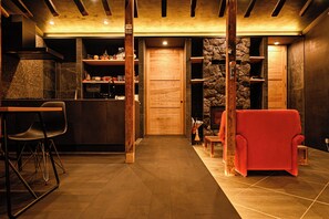 Een modern interieur met een keukenhoek, een houten deur en een rode fauteuil.