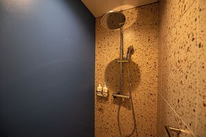 Een douche met een handdouche, een wandmengkraan en een zeepdispenser.