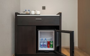A compact minibar with a refrigerator containing bottled water and soda cans. - MEHOOD LESTIE Hotel Qingdao Vientiane (Qingdao)