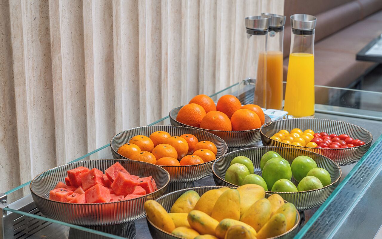 A buffet table with various fruits and a glass partition.