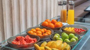 A buffet table with various fruits and a glass partition.