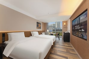 A hotel room with two beds, a desk, a chair, a TV, and a city view.