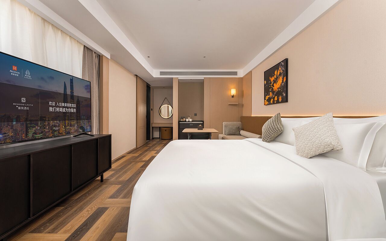 Une chambre d’hôtel avec un grand lit, un téléviseur posé sur un meuble, une petite table et une chaise.