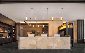 Un comptoir d’accueil avec un plateau en marbre, un éclairage suspendu et un aménagement intérieur moderne.