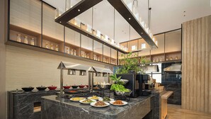 Una cocina moderna con una isla de mármol, electrodomésticos de acero inoxidable y una variedad de vajilla exhibida en estantes.