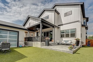 Ein modernes, zweistöckiges Haus mit überdachter Terrasse, Garage und gepflegtem Rasen.