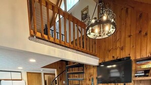 Un salón estilo loft con chimenea, una escalera y una televisión.