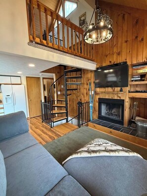 Ein Wohnzimmer im Loft-Stil mit Kamin, Treppe und Fernseher.
