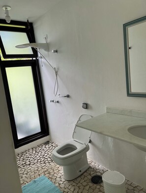 Une salle de bain avec des toilettes, une douche, un lavabo et une fenêtre.