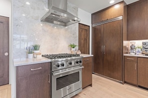 Eine moderne Küche mit Edelstahlkochfeld, Backofen und Holzschränken.