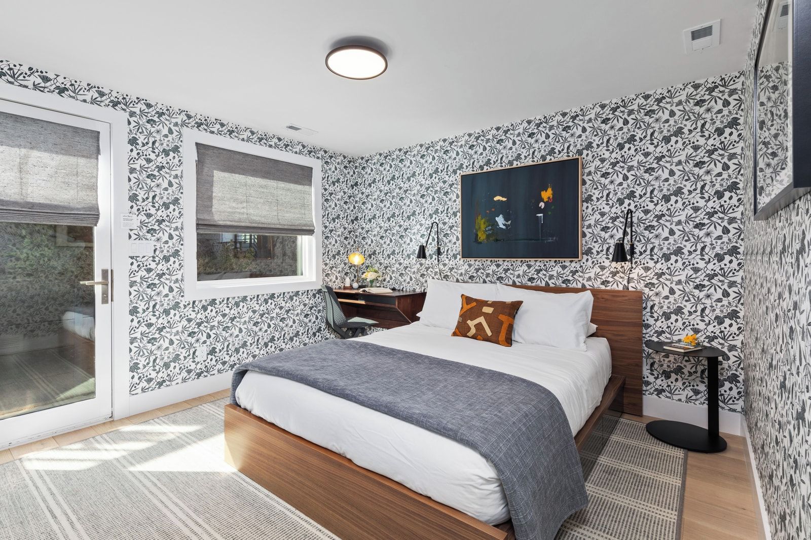 Un dormitorio con cama, ventana, escritorio y un cuadro en la pared.