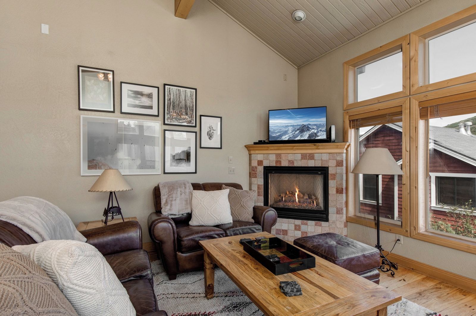 A cozy living room with a fireplace, leather furniture, and framed pictures on the wall.