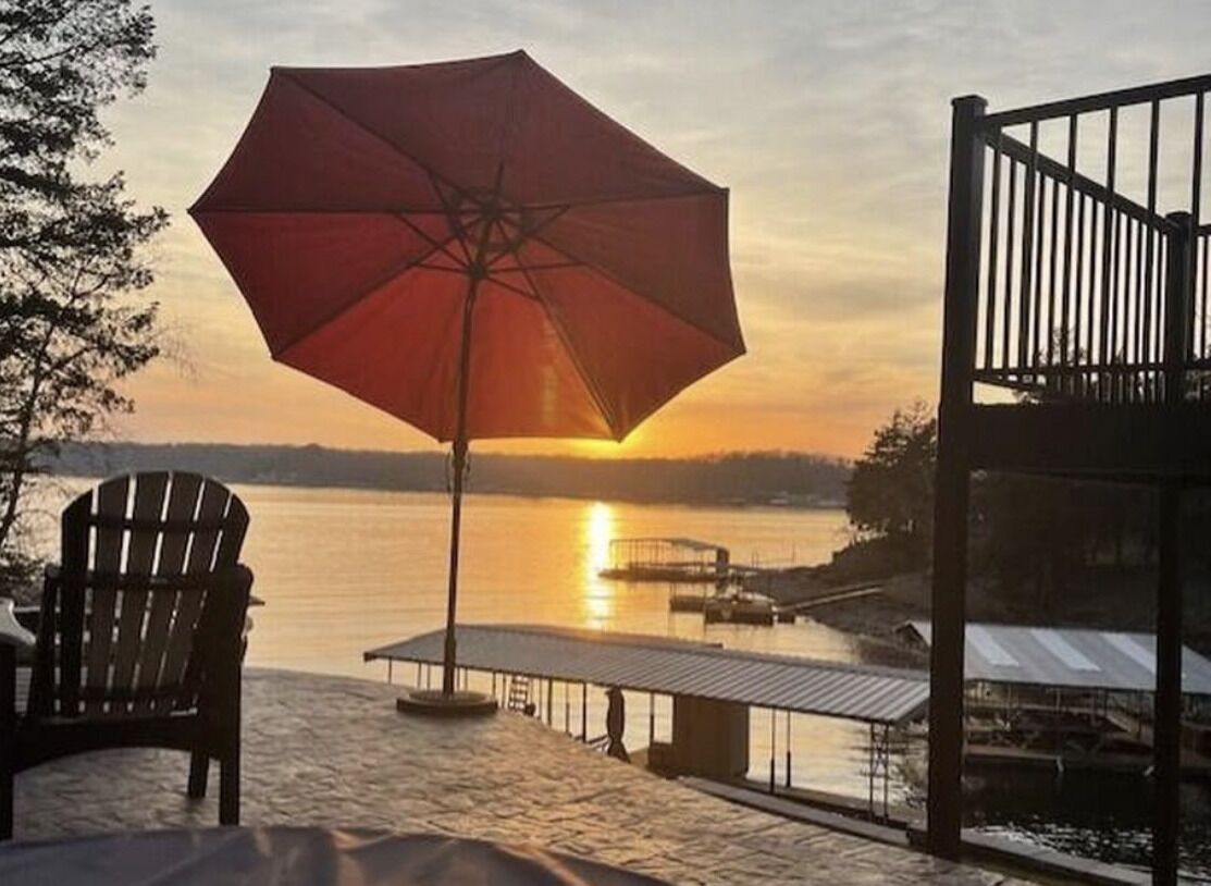 En patio ved vandet med parasol, stol og en anløbsbro.