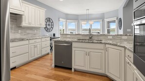 Une cuisine moderne avec des meubles blancs, un lave-vaisselle et une vue sur l’extérieur.