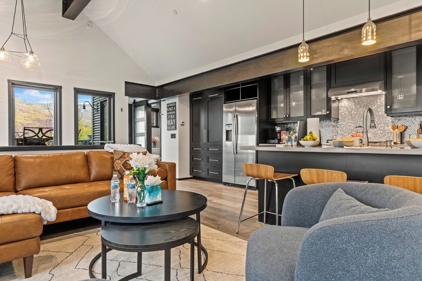 Una cocina moderna con electrodomésticos de acero inoxidable, un comedor con una mesa redonda y sillas, y una sala de estar con sofá y mesa de centro.