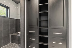 A bathroom with dark tiles, a shower area, and a tall cabinet with multiple drawers. - Walk to Ski Slopes + Trails! 2 Mountain View Homes, 7 Bedrooms, with Private Hot Tubs, Fireplaces, and AC | ML-3981 by KBM (Park City)