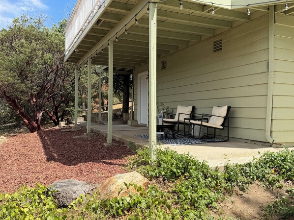 A covered porch with outdoor seating, a pathway leading to a door, and a landscaped garden with mulch and rocks. - Julian Hilltop Hideaway (Julian)