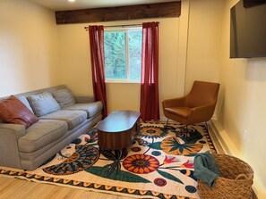 A living room with a sofa, a chair, a coffee table, a patterned rug, and a window with curtains. - Julian Hilltop Hideaway (Julian)