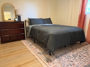 A bedroom with a bed, dresser, mirror, and patterned rug. - Julian Hilltop Hideaway (Julian)