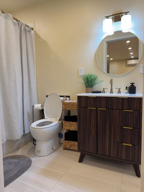 A bathroom with a toilet, a sink with a mirror, a potted plant, and a shower curtain. - Julian Hilltop Hideaway (Julian)