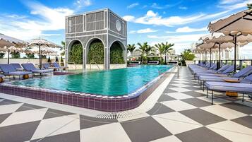 Un espace piscine avec un sol à carreaux, des chaises longues et des parasols.
