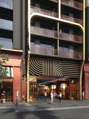 Ein mehrstöckiges Gebäude mit moderner Architektur, mit Balkonen und filigranen Geländern sowie einem geschwungenen Eingang.