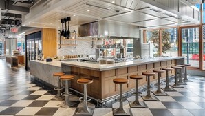 Un'area bar moderna con isola centrale, sgabelli e vista sulla città attraverso ampie finestre.