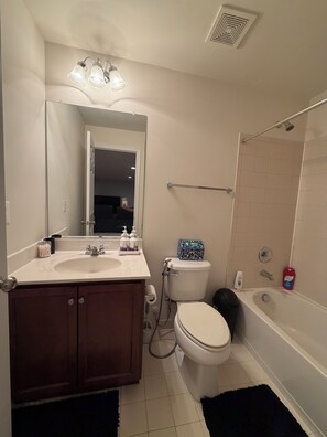 A bathroom with a sink, mirror, toilet, shower, and a towel rack. - Cozy 2-bedroom basement in charming Gainesville (Gainesville)